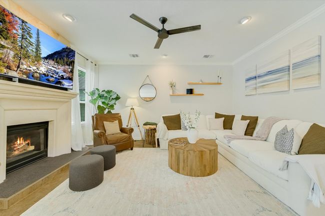Living area featuring ceiling fan, wood finished floors, ornamental molding, and a high end fireplace | Image 7