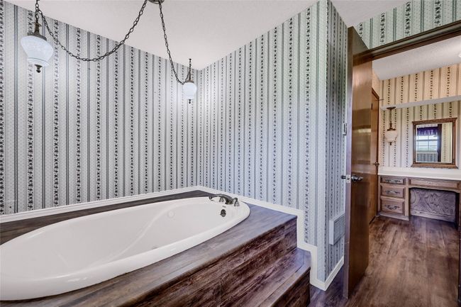 Bathroom featuring a bath, baseboards, wallpapered walls, and wood finished floors | Image 21
