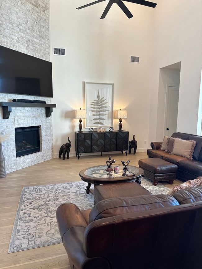 Living area with a stone fireplace, wood finished floors, and visible vents | Image 11