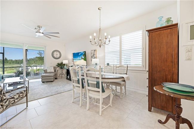 Dining space with healthy amount of natural light, light tile patterned floors, and a chandelier | Image 16