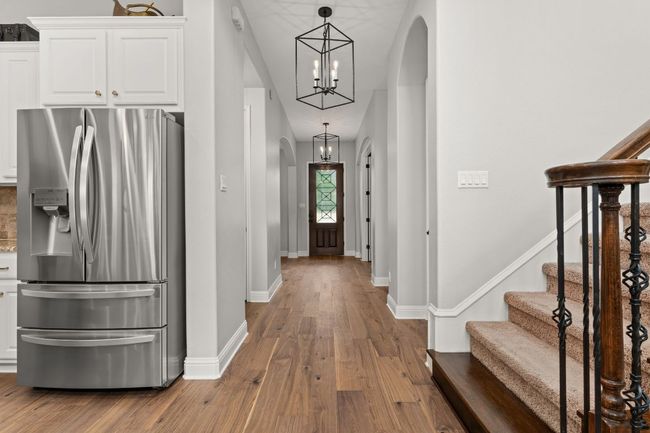 Entryway featuring arched walkways, baseboards, wood finished floors, and a chandelier | Image 4