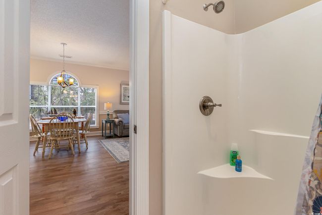 Bathroom featuring ornamental molding, a textured ceiling, a shower, hardwood / wood-style flooring, and an inviting chandelier | Image 14