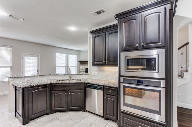 Kitchen featuring kitchen peninsula, stainless steel appliances, light stone counters, and sink | Image 14
