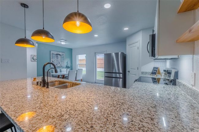 Other upgrades include a kitchen disposal, smart lighting, reverse osmosis filtered water, open shelving in beautiful natural wood, and stylish cabinet hardware. Just look at the counter space! You have room to add a kitchen island cart if you would like. The corner pantry is just the right size for all your kitchen needs. | Image 11