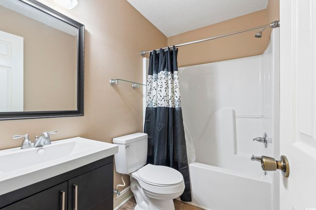 Full bathroom featuring toilet, shower / bath combo with shower curtain, vanity, and a textured ceiling | Image 16