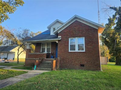 Bungalow-style house with a front lawn, covered porch, and a garage | Image 2