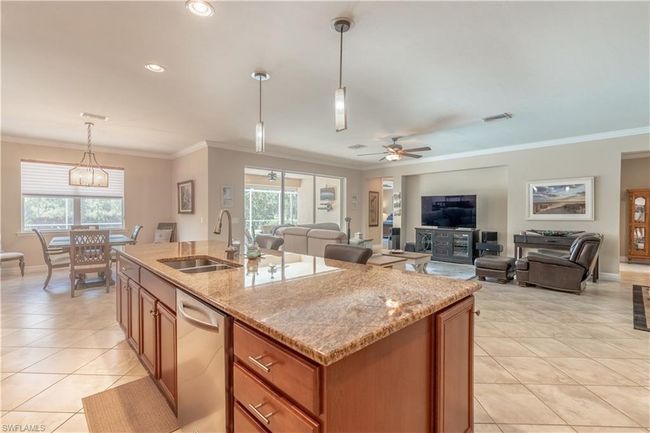 Living room featuring light tile patterned flooring, sink, crown molding, and ceiling fan | Image 17