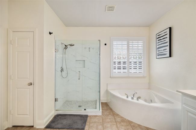 Full bath with a garden tub, vanity, tile patterned flooring, visible vents, and a marble finish shower | Image 18