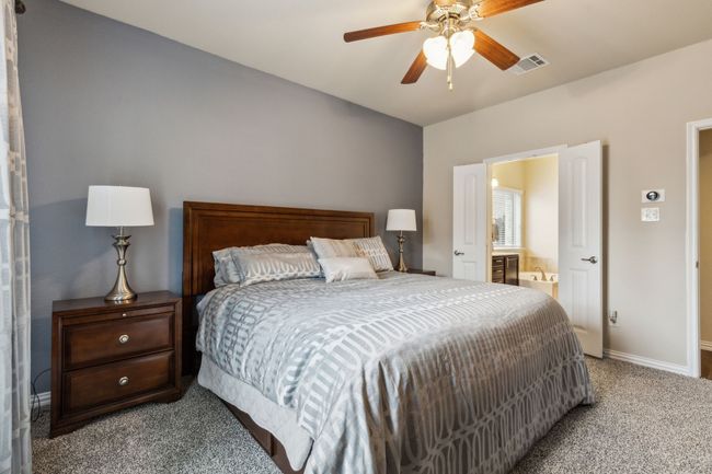 Carpeted bedroom with baseboards, connected bathroom, and ceiling fan | Image 13