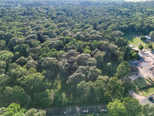 Aerial view highlights dense tree coverage and prime road frontage. Ideal for commercial development, flex space, or land hold. No zoning or deed restrictions allows for flexible use and long-term upside. | Image 9