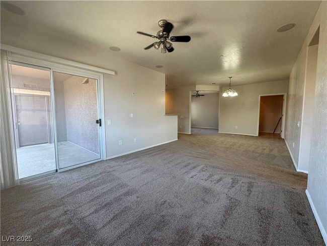 Carpeted empty room with ceiling fan and a chandelier | Image 6