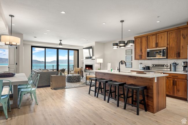 Kitchen featuring stainless steel appliances, brown cabinets, a sink, light wood finished floors, and open floor plan | Image 56