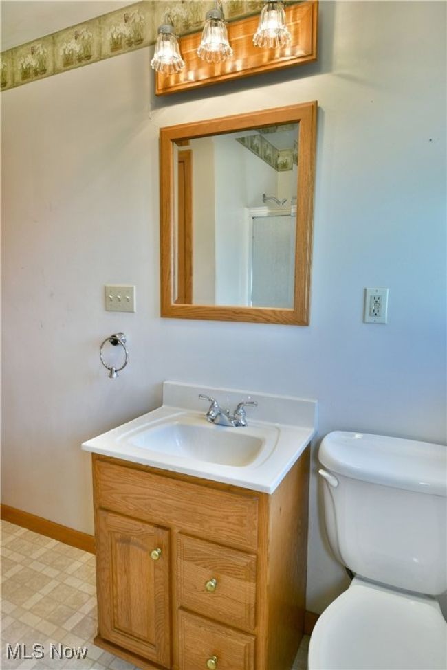 Bathroom with toilet, vanity, tile patterned floors, and baseboards | Image 32