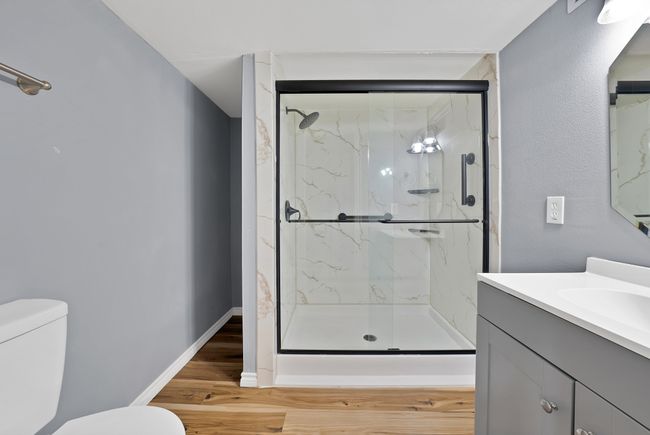 Full bath featuring a marble finish shower, vanity, and wood finished floors | Image 10