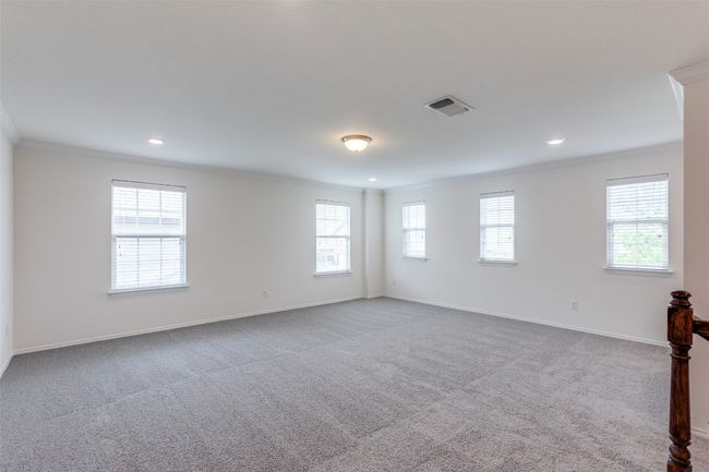 Carpeted spare room featuring a healthy amount of sunlight, ornamental molding, and visible vents | Image 12