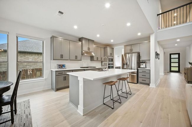 Kitchen featuring gray cabinets, stainless steel appliances, plenty of natural light, an island with sink, and recessed lighting | Image 11