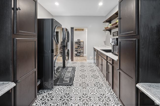 Laundry area featuring stacked washer and clothes dryer, light tile patterned floors, recessed lighting, and baseboards | Image 50
