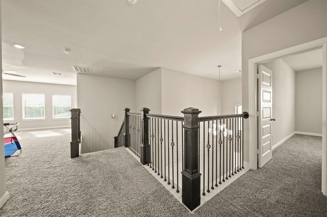 Upstairs landing with elegant wrought iron railings and chandelier view. | Image 36