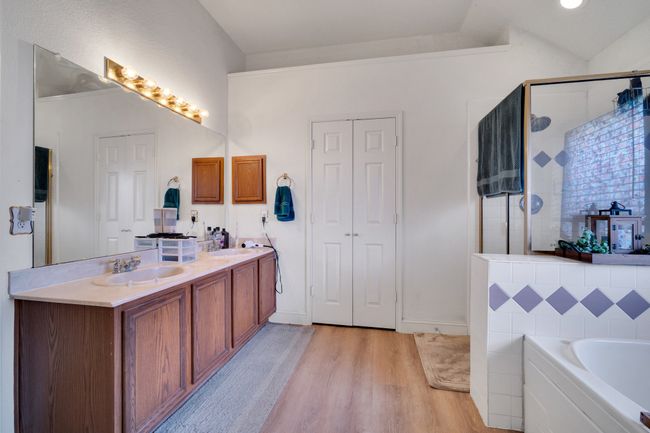 Full bathroom featuring wood finished floors, double vanity, a bath, and a stall shower | Image 27