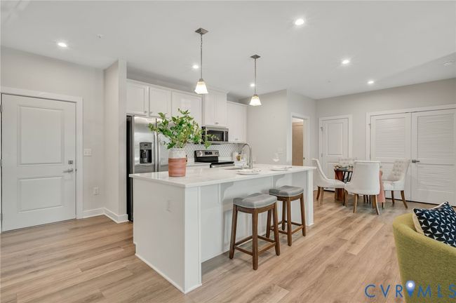 Kitchen featuring recessed lighting, a kitchen breakfast bar, white cabinets, an island with sink, and light wood-style flooring | Image 5