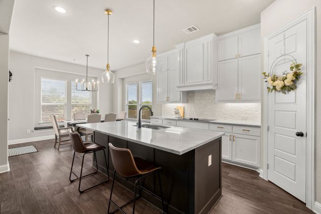 Kitchen with dark wood-style flooring, backsplash, recessed lighting, white cabinetry, and a center island with sink | Image 13