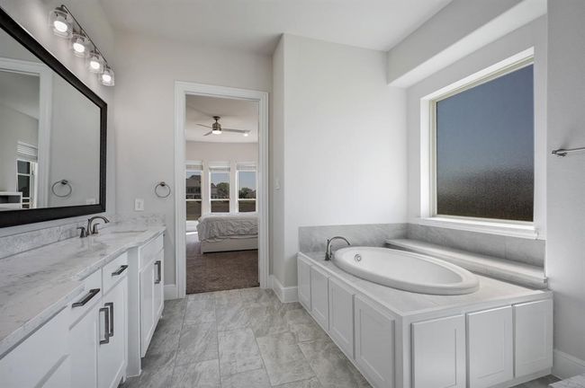 Ensuite bathroom with a ceiling fan, vanity, a garden tub, and baseboards | Image 18