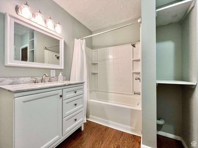 Bathroom featuring shower / bath combination with curtain, vanity, wood finished floors, and a textured ceiling | Image 18