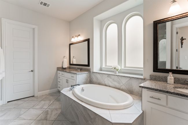 Full bath featuring two vanities, a wealth of natural light, a garden tub, and visible vents | Image 24