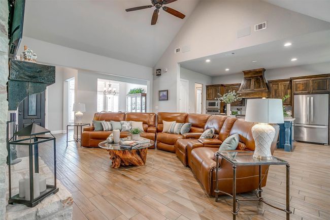Living area featuring high vaulted ceiling, a ceiling fan, a chandelier, light wood-style flooring, and recessed lighting | Image 7