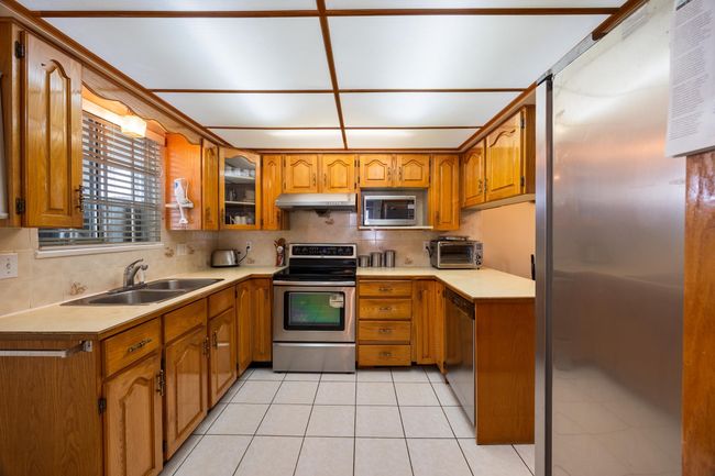 Kitchen with brown cabinetry, a sink, and stainless steel appliances | Image 22