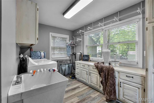 Washroom featuring washer / dryer, a sink, and light wood finished floors | Image 7