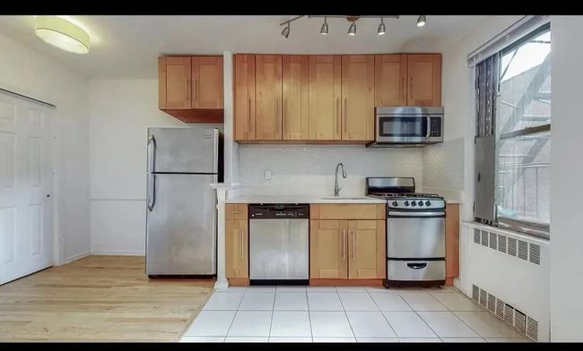 Kitchen with stainless steel appliances, radiator, a sink, light countertops, and decorative backsplash | Image 5