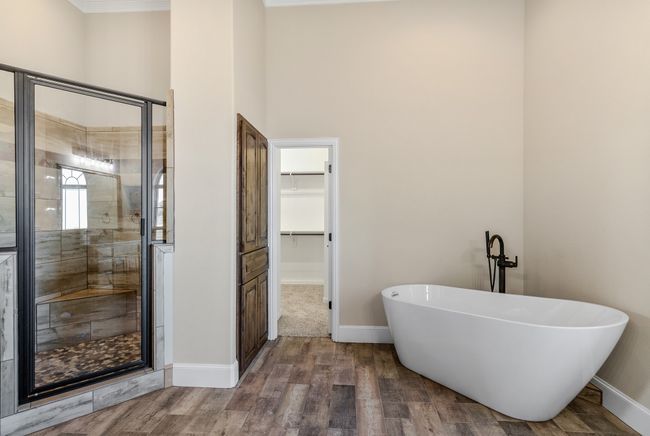 Bathroom with a shower stall, a soaking tub, a walk in closet, baseboards, and a towering ceiling | Image 16