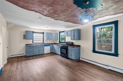 Kitchen with black stove, a baseboard heating unit, and a wealth of natural light | Image 3