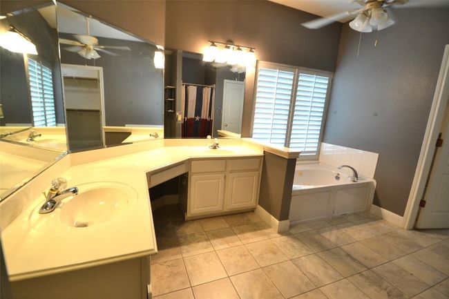 Full bath featuring a ceiling fan, double vanity, a garden tub, and tile patterned floors | Image 13