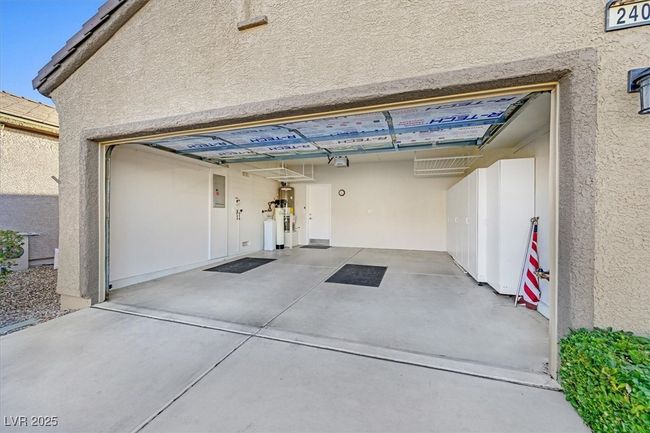 two car garage with built-in cabinets and overhead storage, insulated garage door | Image 26