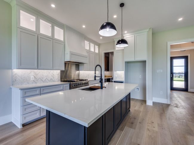Kitchen featuring a sink, light wood-type flooring, backsplash, stove, and white cabinets | Image 24