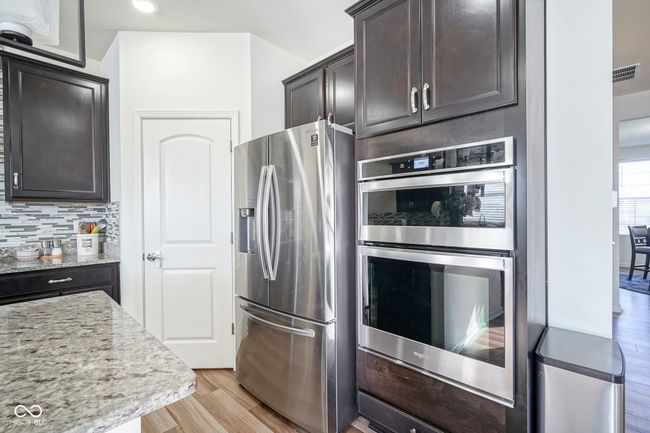 kitchen featuring tasteful backsplash, stainless steel appliances, light stone counters, light wood-style floors, and visible vents | Image 19