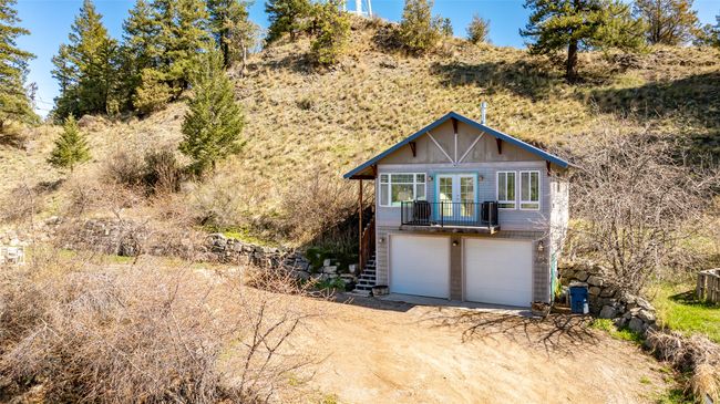 View of front of home with an attached garage, stairway, dirt driveway, and french doors | Image 51
