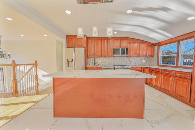 Kitchen featuring decorative light fixtures, decorative backsplash, ornamental molding, a center island, and stainless steel appliances | Image 21