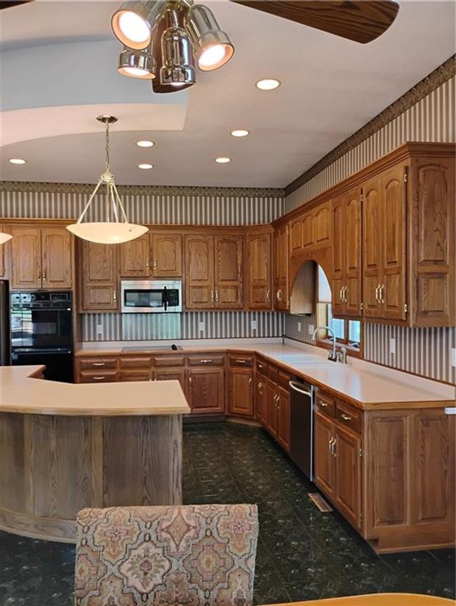 Kitchen with light countertops, multiple ovens, dishwashing machine, and a sink | Image 33