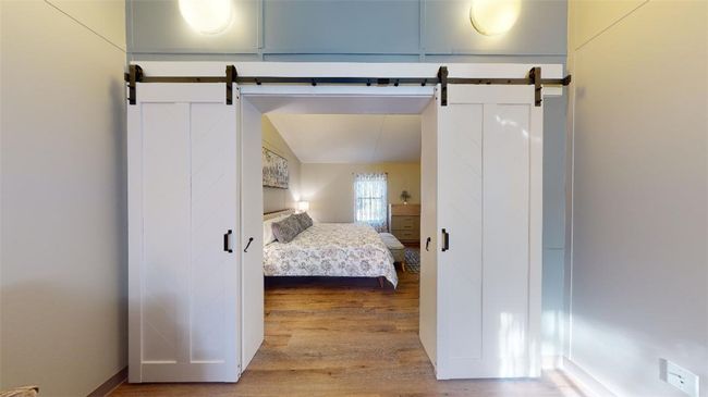 Bedroom featuring a barn door, wood finished floors, and vaulted ceiling | Image 20
