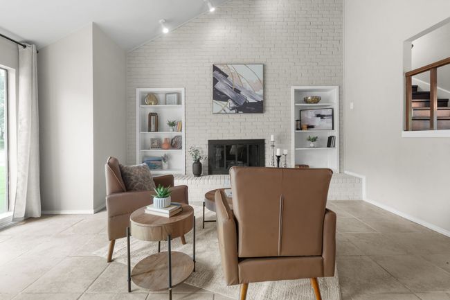 Living room featuring built in shelves, lofted ceiling, plenty of natural light, and a fireplace | Image 4