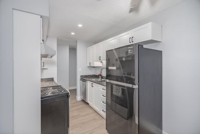 Kitchen featuring appliances with stainless steel finishes, a sink, white cabinets, light wood finished floors, and recessed lighting | Image 8