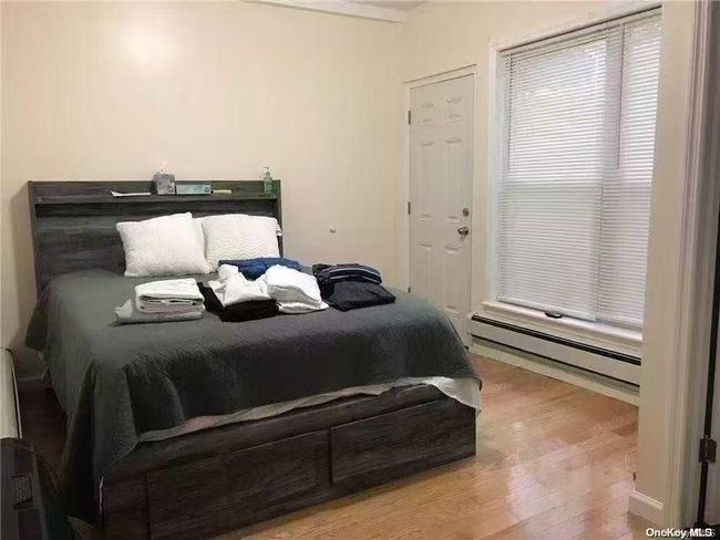 Bedroom featuring baseboard heating and wood finished floors | Image 4