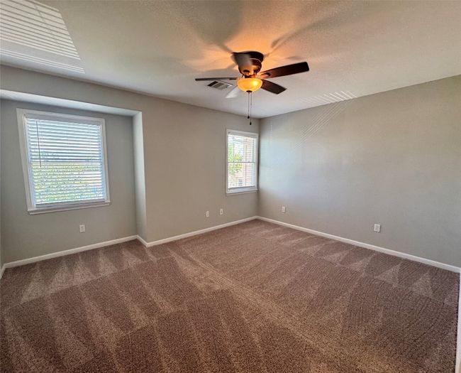 Empty room featuring ceiling fan and dark colored carpet | Image 12