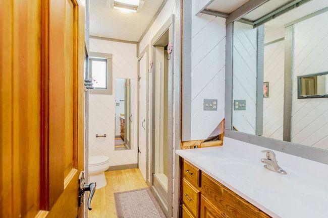 Full bath featuring vanity, wooden walls, and wood finished floors | Image 7