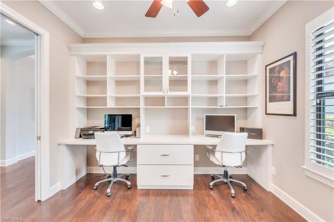 Unfurnished office with built in desk, wood finished floors, a ceiling fan, ornamental molding, and baseboards | Image 19