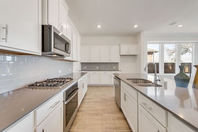 Kitchen with stainless steel appliances, white cabinetry, decorative backsplash, recessed lighting, and light wood-type flooring | Image 6