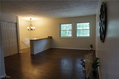 Empty room featuring a notable chandelier, dark hardwood / wood-style flooring, and a textured ceiling | Image 2